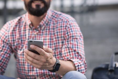 Smiling adult man using his phone outdoorsの写真素材