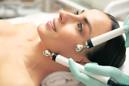 Close up of smiling lady during the microcurrent therapyの写真素材