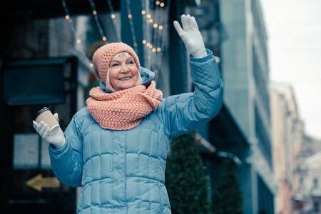 Positive pensioner waving her hand and smilingの写真素材