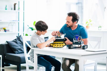 Involved man and his little son constructing robotic devicesの写真素材