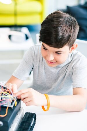Smart positive schoolboy constructing a robotic device