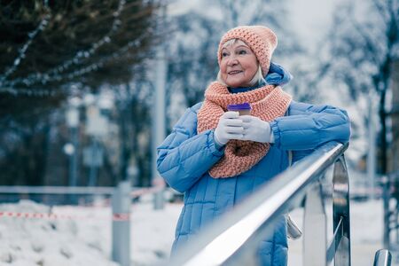 Positive elderly woman putting elbow on the handrail outdoorsの写真素材