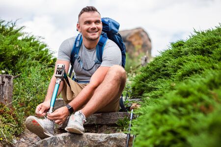 Joyful man with prosthesis tying his shoelaceの写真素材