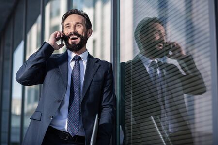 Overjoyed smiling businessman standing against glass wallの写真素材