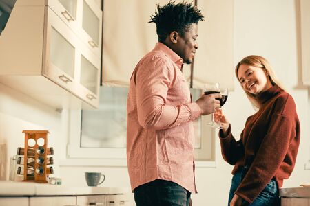 Cheerful lady smiling while clanging glasses with young man