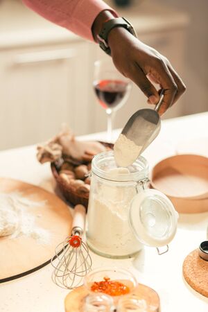 Close up of man getting flour from the glass jar