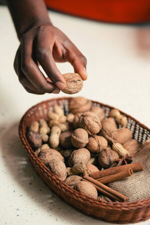 Close up offhand taking walnut from the basket on the tableの写真素材