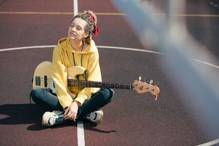 Peaceful female musician enjoying the sunlight and closing her eyes