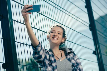 Young woman feeling happy while holding smartphone and taking selfies