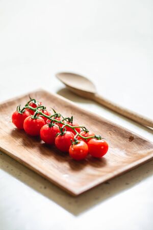 Close up of cherry tomatoes on the plate and wooden spoonの写真素材