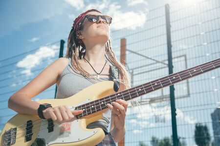 Talented musician frowning while playing the guitar in sunny dayの写真素材