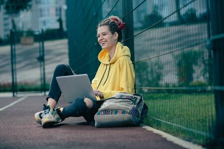 Happy young lady laughing while sitting alone with her laptopの写真素材