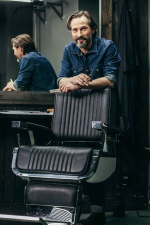 Cheerful bearded man smiling while leaning on the armchairの写真素材