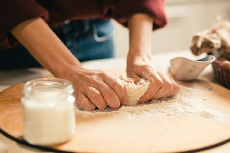 Hands of woman kneading dough on the wooden board