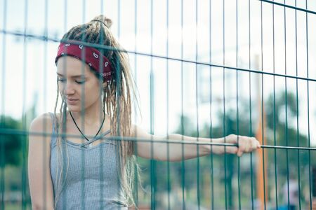 Calm lady thoughtfully looking down and touching the chain link fenceの写真素材