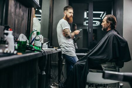 Curious man looking at his barber while sitting in the armchairの写真素材
