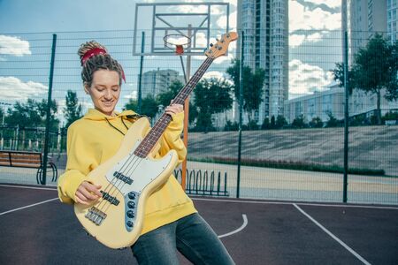 Waist up of young lady smiling and playing the guitar