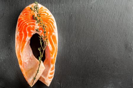 Uncooked res fish slice with thyme on it lying on the slateの写真素材