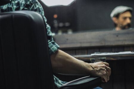 Close up of glass of alcohol in the hand of manの写真素材