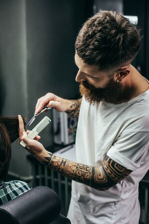 Waist up of bearded barber cutting hair of his clientの写真素材