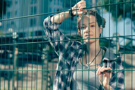 Calm lady looking confident while touching the chain link fenceの写真素材