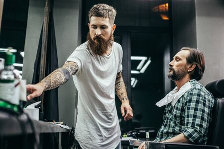 Calm man closing his eyes while professional barber workingの写真素材