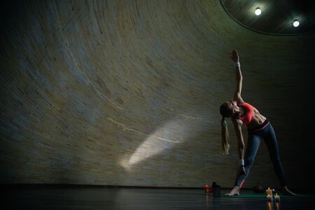 Full length of young woman standing in triangle pose on yoga matの写真素材