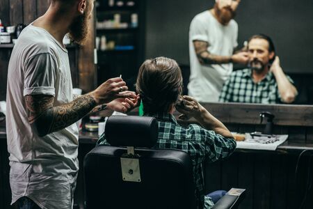 Man touching his hair while professional barber workingの写真素材