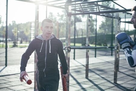 Calm trainer walking with boxing sticks and talking to the boxerの写真素材