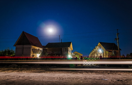 wooden houses in the moonlight, the light from the headlightsの写真素材