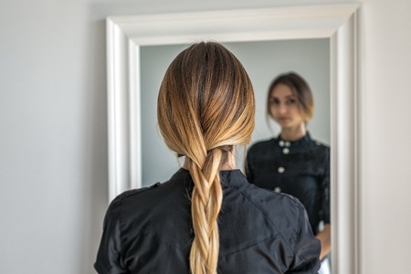 woman girl with ombre hairstyle in braid in front of mirrorの写真素材