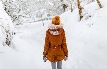 girl or woman walk winter outdoor, snowy cold weather, countryside blizzard snowfall, yellow hatの写真素材