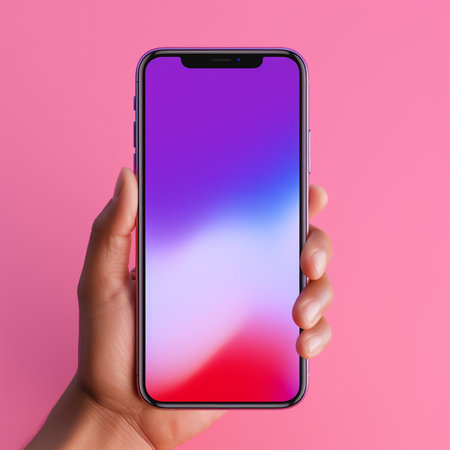 Female hand holds a smartphone with a blank screen on a pink backgroundの素材