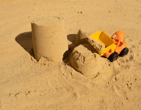 childrens toy yellow-orange tractor on the beach working with sand. close upの写真素材