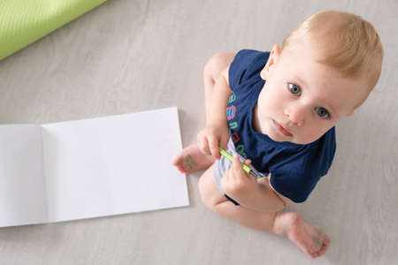 boy drawing in a drawing box sitting on the floor looking at the camera. copy spaceの写真素材