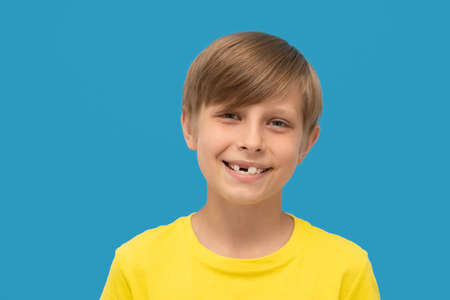 close up photo blond boy in yellow t-shirt shows a smile without front tooth.の写真素材