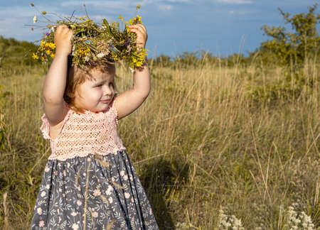 toddler girl with wildflowers wreath. carefree childhood mood.の写真素材