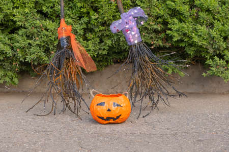 close up photo two witch brooms and homemade orange pumpkin.の写真素材