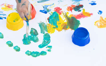 Childrens hand with with paint and brush. Children creative hobby. drawn sheet of paper.の写真素材