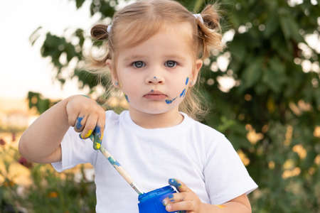 blonde girl with a jar of paint and a brush.の写真素材