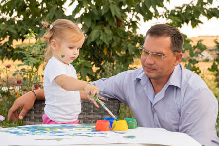 Happy father and adorable little daughter enjoying leisure time together. kid girl learning painting with father.の写真素材