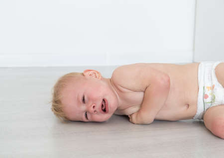 baby blonde boy crying lying on the field.