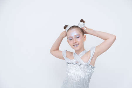 girl in a silver dress holds her ponytails with her eyes closed.の写真素材