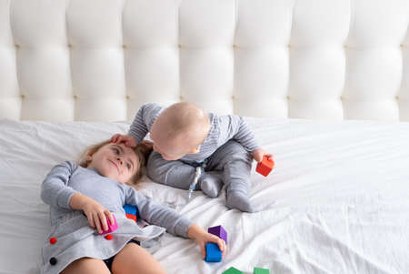 baby boy and little girl sister playing wooden toys at home on bed. Home activities for kids.