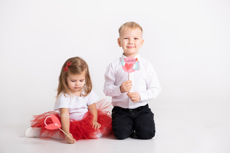 boy and toddler girl holds the toppers or stikcers with valentines day design on white backgroundの写真素材