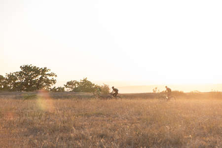 cyclists ride along the trail at sunset.
