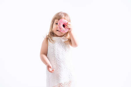 Funny child girl in white dress with pink donut on white background.