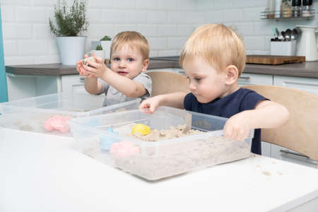 two blonde boys twins play with kinetic sand at home. Creative play for kids.の写真素材