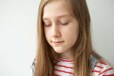 portrait of beautiful teenage girl with long hair smiling standing against white wall.の写真素材