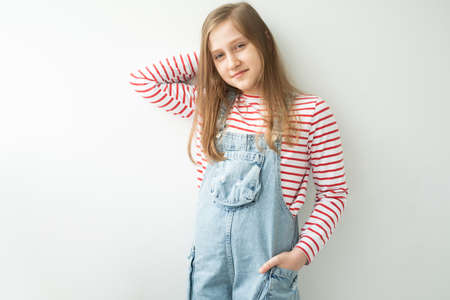 beautiful teenage girl with long hair standing against white wallの写真素材